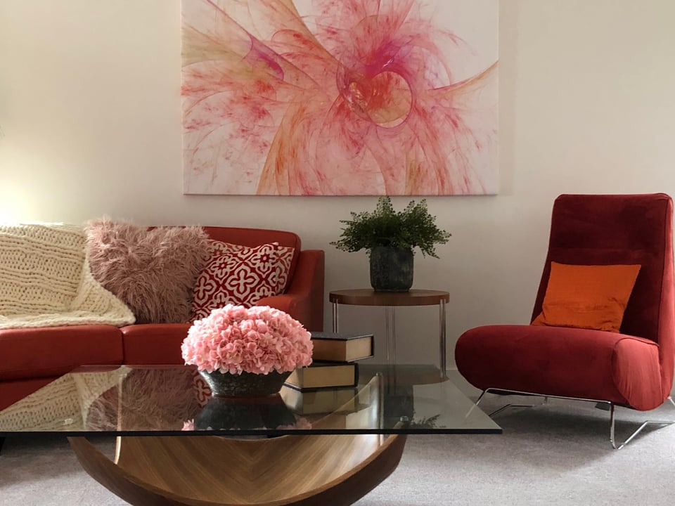 living room with couch and accent chair around glass coffee table with vibrant art piece