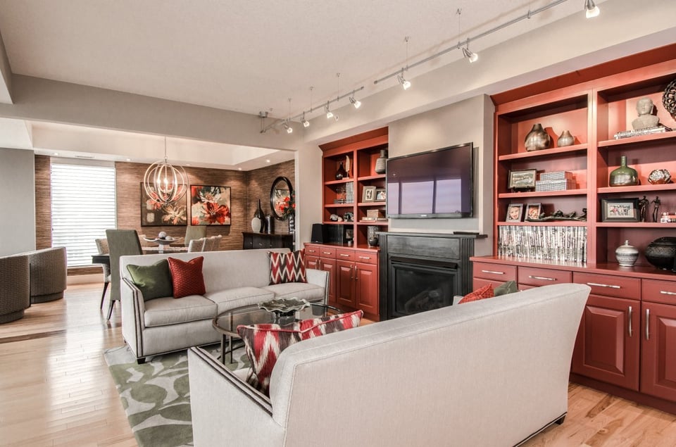 living room with two couches in front of a dining room with hanging chandelier