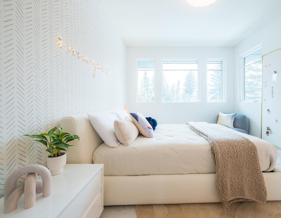 clean bedroom with upholstered bed frame and the word imagine over the bed as decor