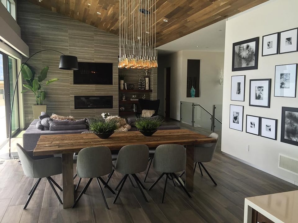 wooden dining table with eight upholstered chairs in front of a living room with sectional and television