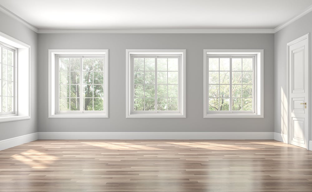 an empty room with four large windows, a closed door, and hardwood floors