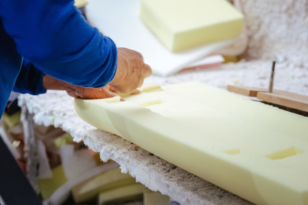 close up of a furniture maker's hands shaping an upholstery foam