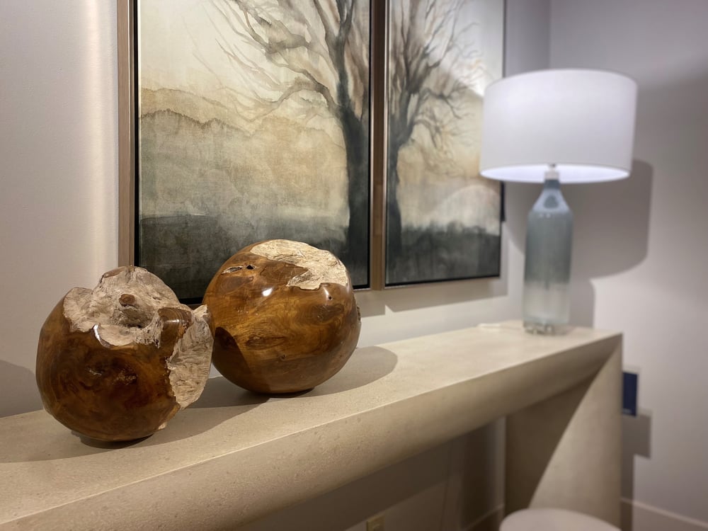 two wooden decorative balls on top of a console table with a lamp nearby in front of two matching pictures