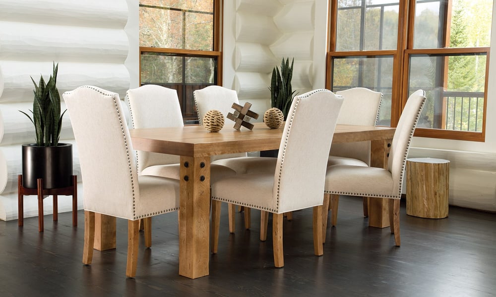 open dining room with solid wood table, six upholstered chairs with nail head detail, and wood accents