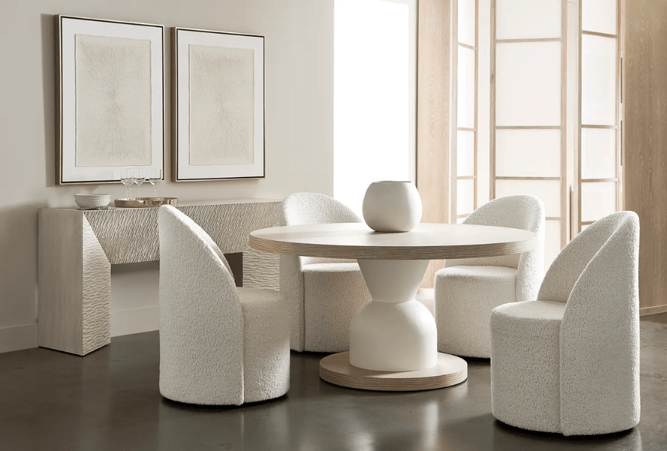 dining room with small round table and four completely upholstered dining chairs next to a buffet table under two decorative pictures