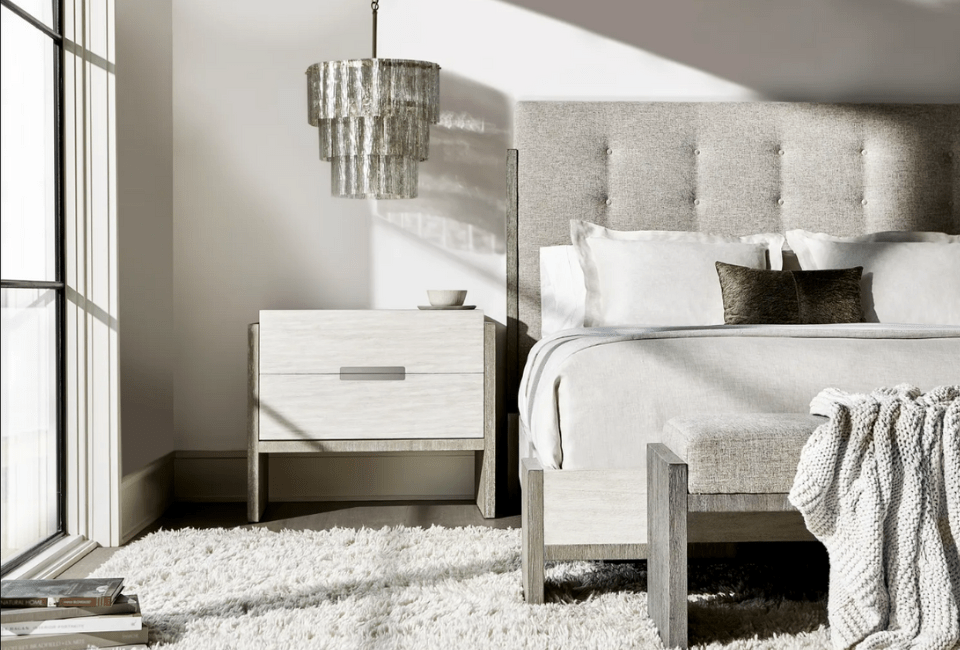 bed with an upholstered headboard beside a nightstand and a small chandelier