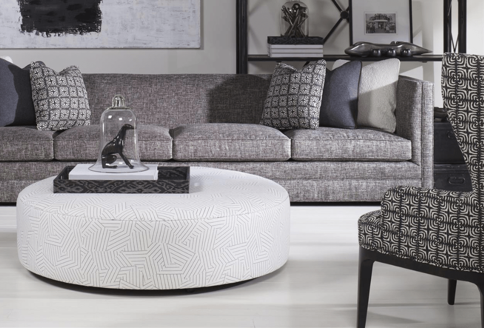 living room setting with fabric sofa and chair around an upholstered circular ottoman
