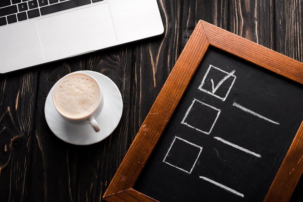 Top view of chalk board with checklist near cup of coffee