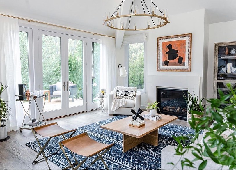 living room with coastal design, a sofa, three chairs, and wooden coffee table sit on top of an accent area rug