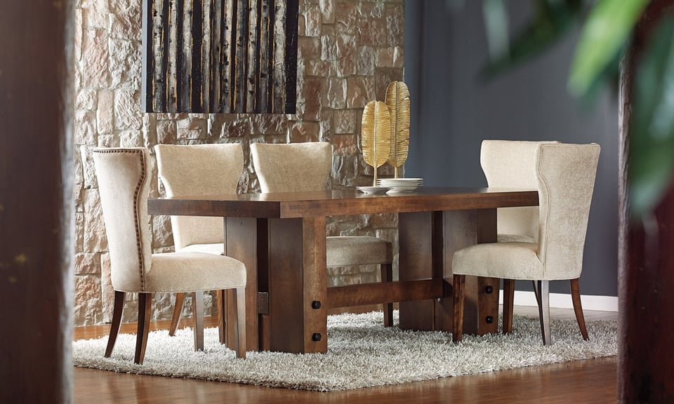dining room set with wood table and five upholstered chairs in front of a stone wall