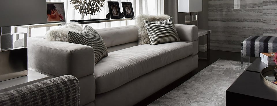 sofa with bench seat and four pillows in front of a sofa table and window