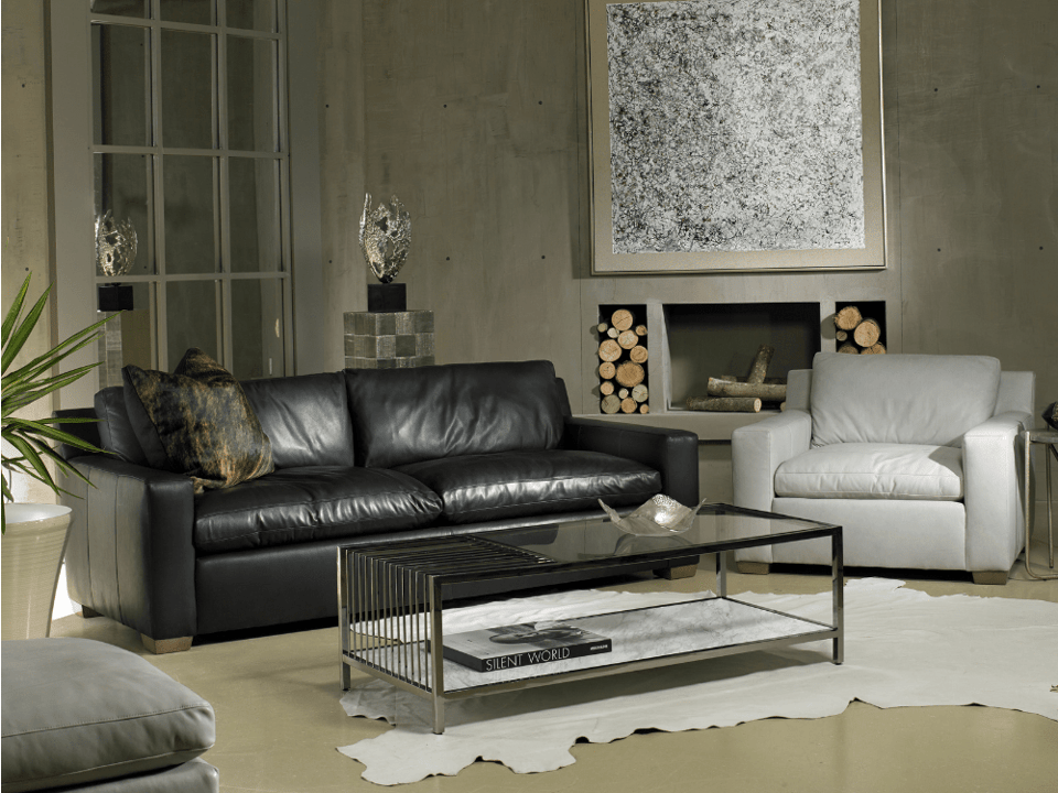 leather sofa with leather chair and leather ottoman around a glass and metal table over a hide rug in front of a fire place with extra logs