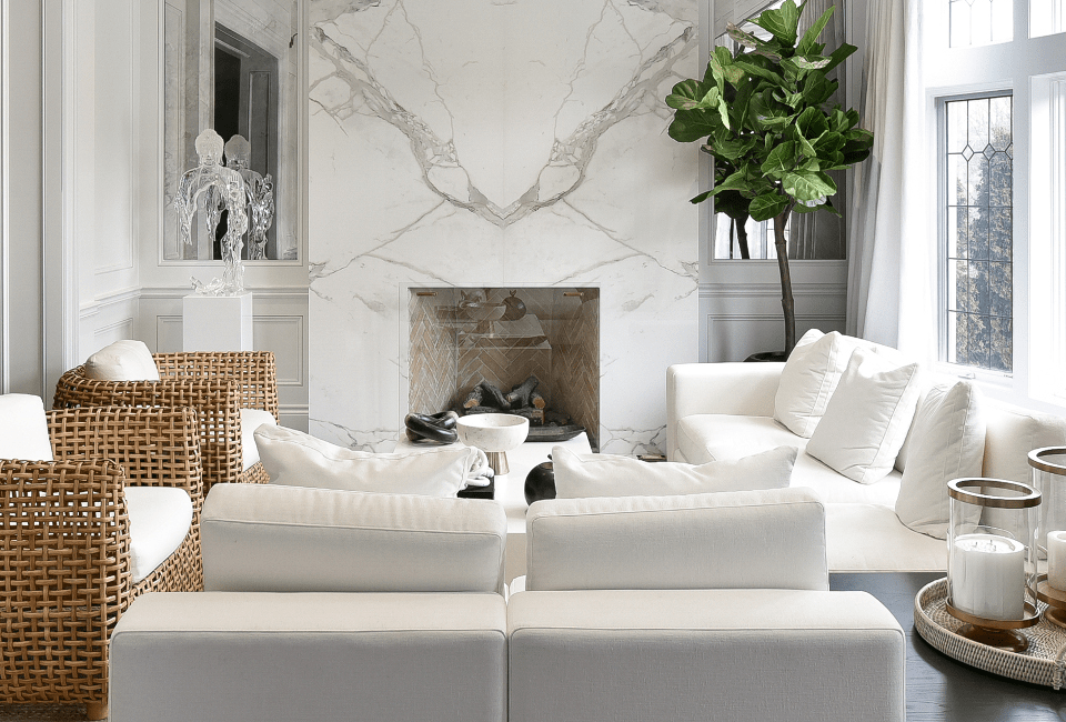 living room setting with two sofas and two matching wicker accent chairs in front of a marble fireplace