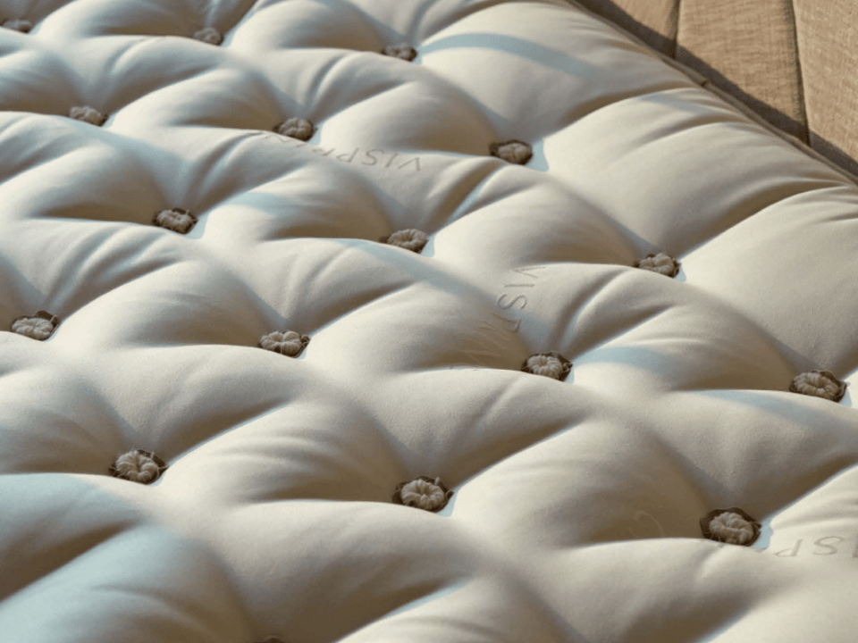 top of an innerspring, Vispring mattress with tufting, in front of an upholstered headboard