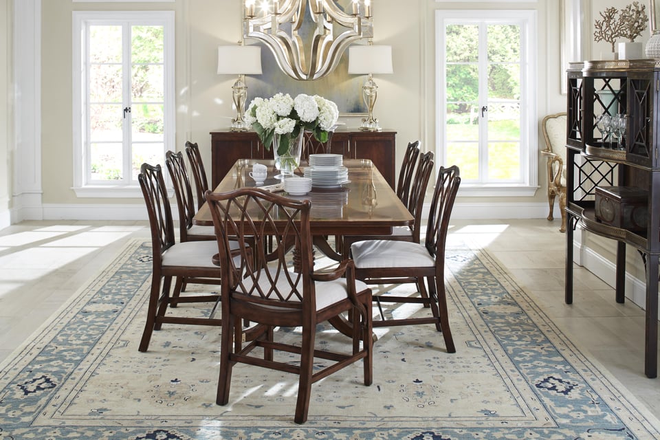 long wooden dining table with eight chairs with a floral centrepiece and plates