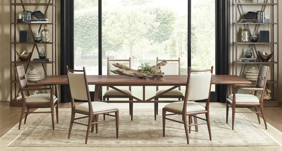 wooden dining table with six upholstered chairs over area rug with bookshelf