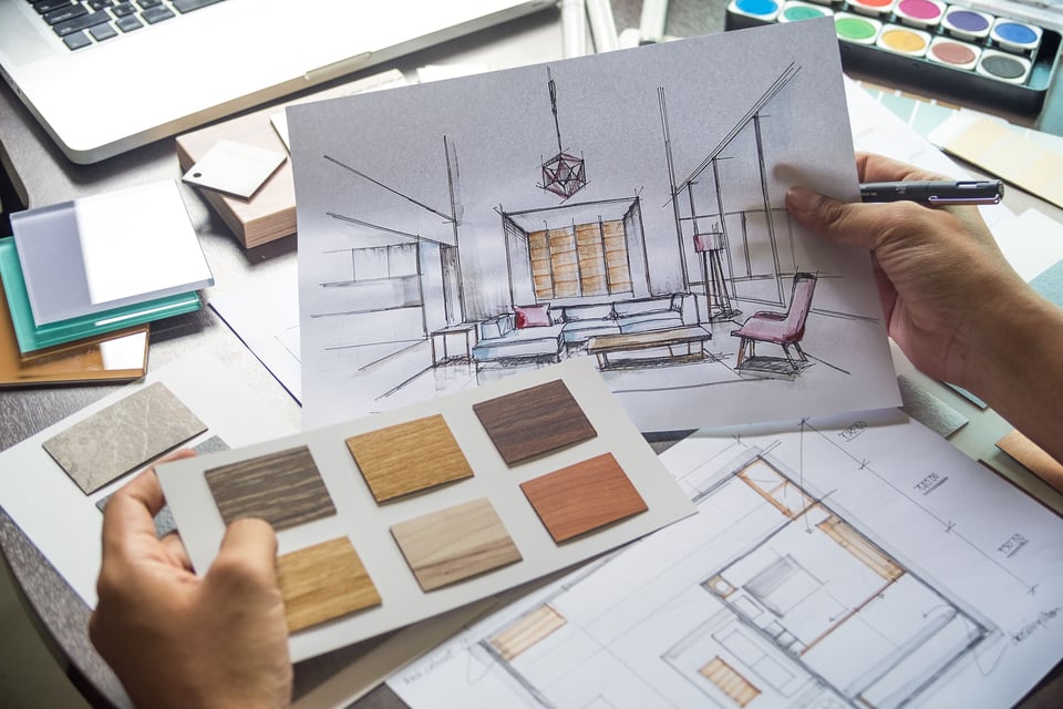 point of view of designer looking at flooring samples and hand drawn layout of a living room