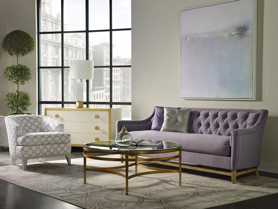 tufted sofa and patterned accent chair around a round glass top coffee table over an area rug