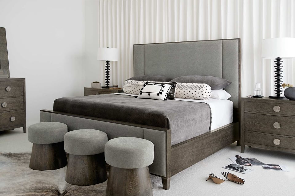 bedroom suite with wooden bed frame, upholstered headboard and footboard, three matching stools at foot of the bed and complementary bedroom pieces, like nightstands and dresser