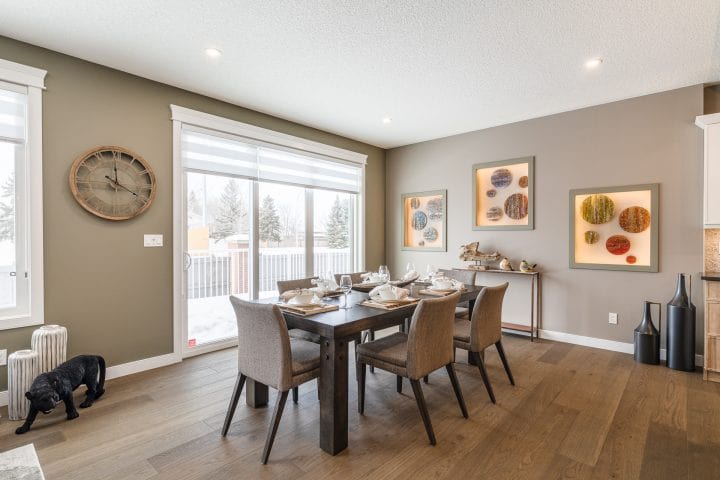 dining room with wood table, place settings, wine glasses, and six upholstered chairs with a console table underneath three decorative pictures