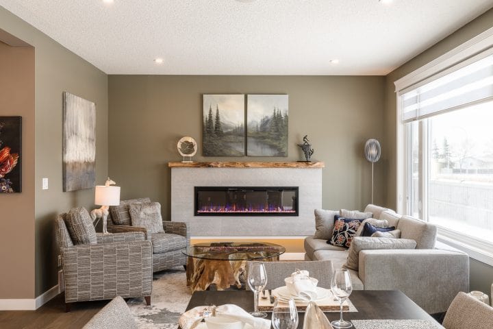 living room with track arm sofa and two matching chairs around a teak and glass coffee table by an automatic fireplace