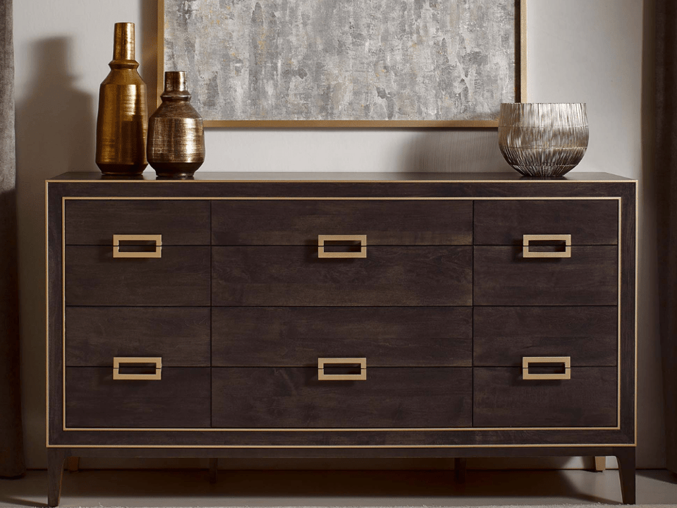 three column wood dresser with rectangular handles, three decorative vases on top with a large picture behind