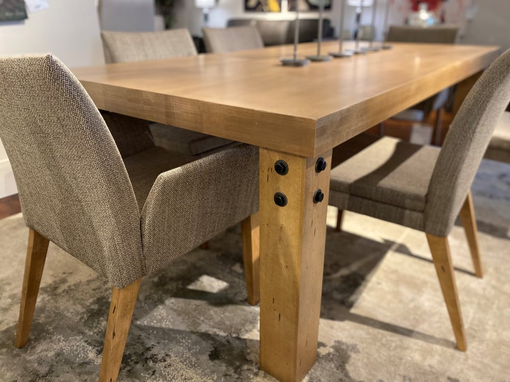 close up of a solid wood leg of a table with four industrial bolts