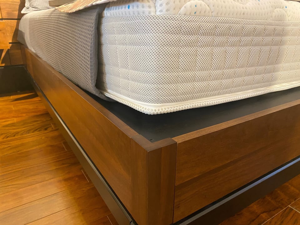 close up of a platform bed with a mattress on top and blankets loosely laid on top