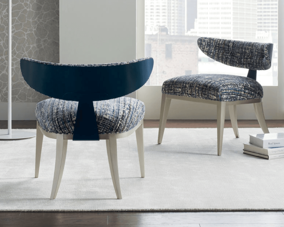 two half moon chairs from Caracole over an area rug with books on the floor