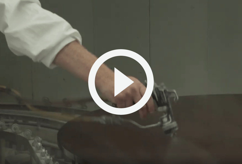 still of a video of a man catalyzing and varnishing a round, wooden dining table