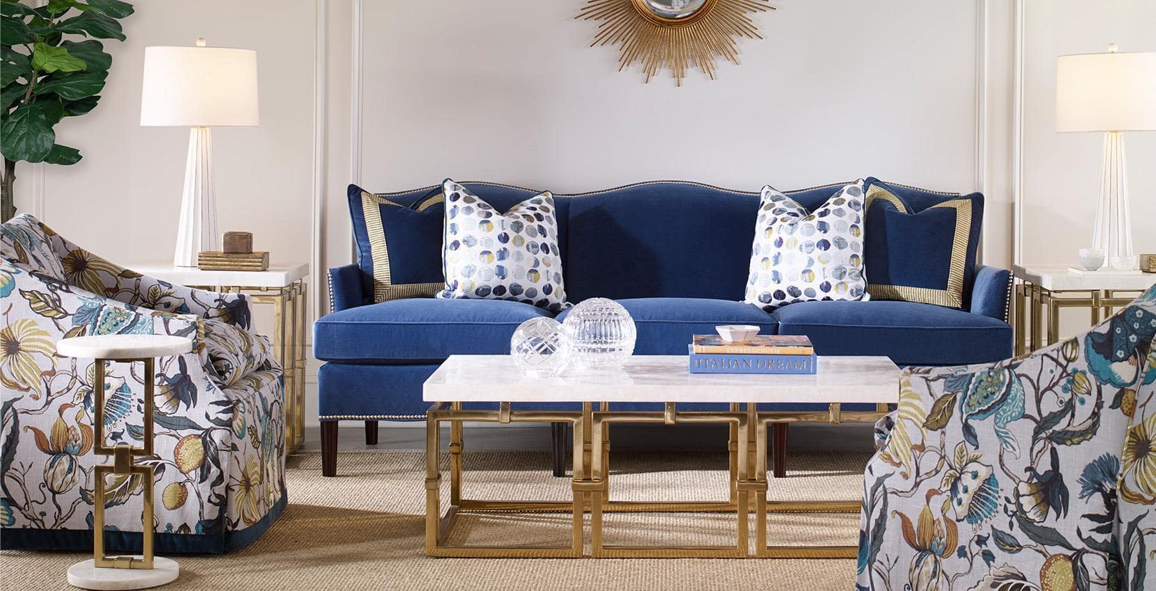 living room setting with traditional velvet sofa, two patterned accent chairs, four matching tables with gold metal and marble tops