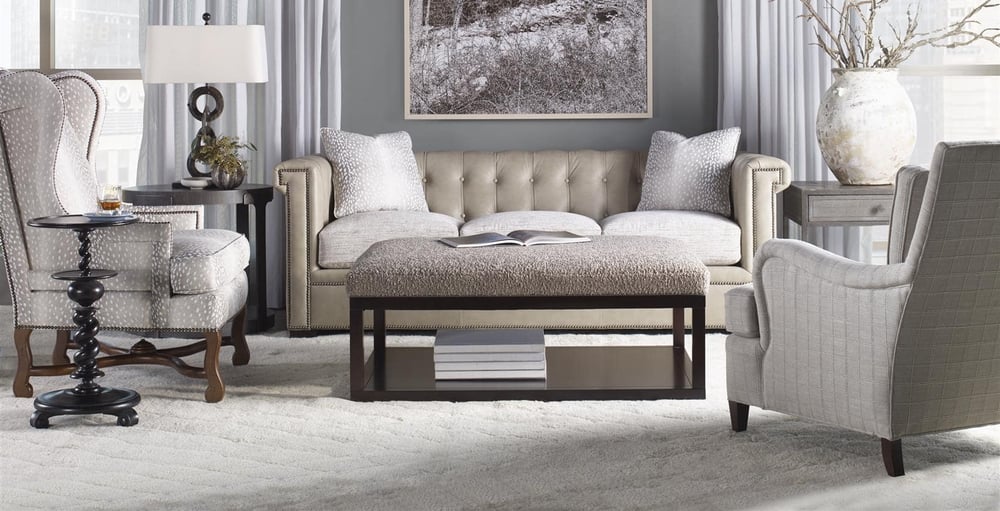 living room setting with a leather sofa and two fabric accent chairs around an upholstered bench over a carpet