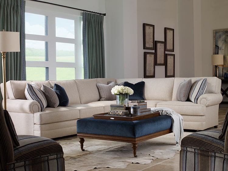 living room with sectional and two accent chairs around an upholstered ottoman with serving tray