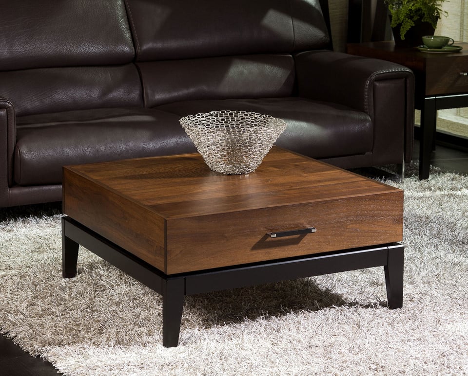 square wood coffee table with a decorative bowl on top in living room over shag carpet in front of a leather sofa