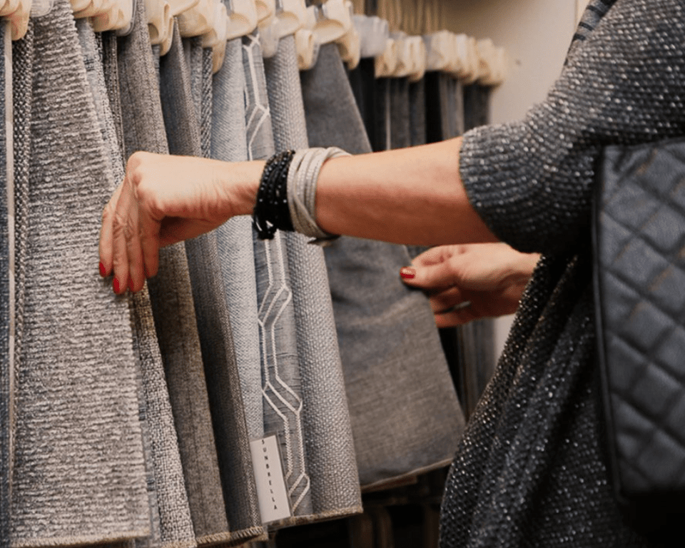 woman goes through a rack of furniture fabrics with hands