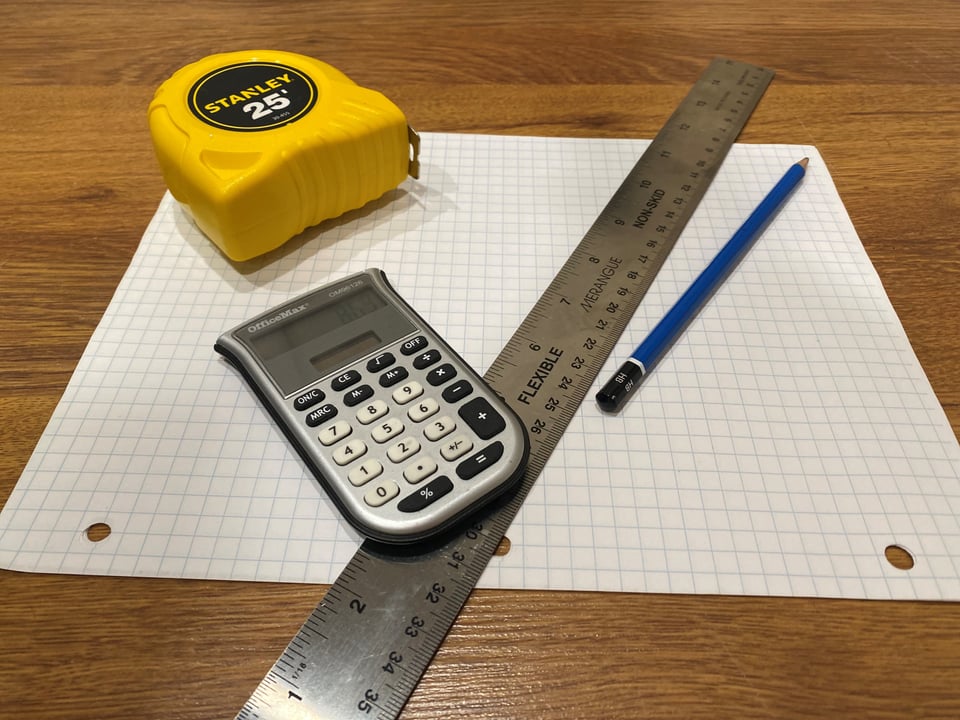 a metal ruler, pencil, calculator, and measuring tape for space planning