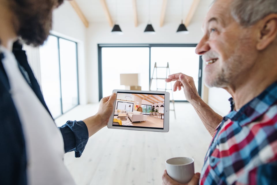 two men look at iPad showing what a room will look like once it is furnished