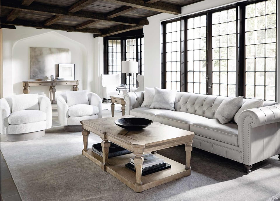 sofa and two accent chairs around a wooden coffee table with bowl centre piece over an area rug