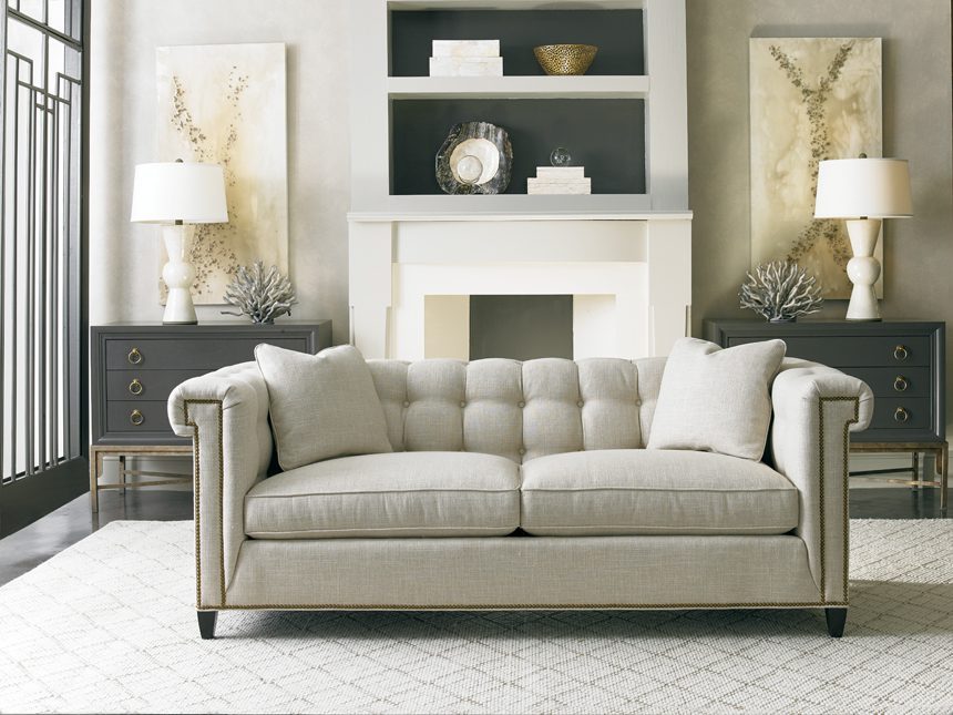 tufted and upholstered sofa in a living room on top of an area rug and in front of a fireplace and two matching dressers