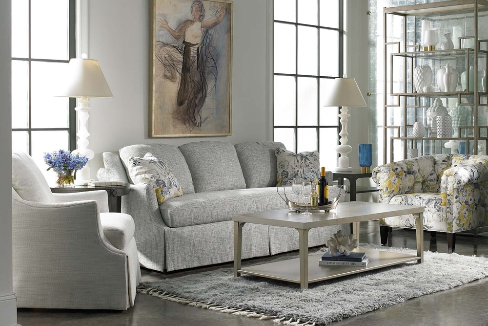 living rom with fabric skirted sofa and two accent chairs around a rectangular coffee table over an area rug
