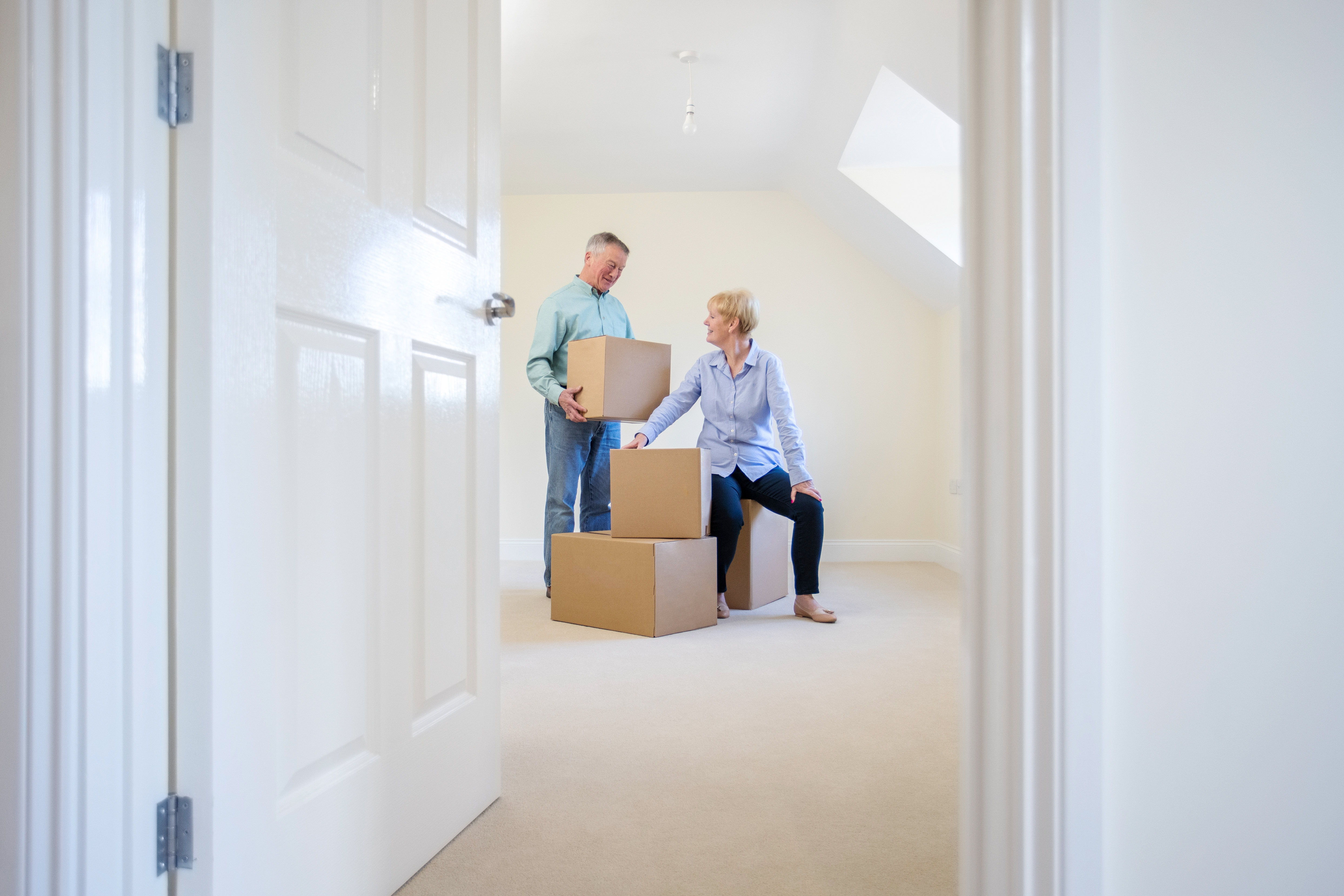 senior couple with moving boxes reflect on a room they are moving out of