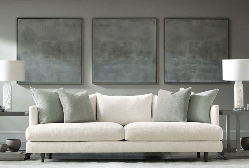 deep seated two cushion sofa in front of three large pictures