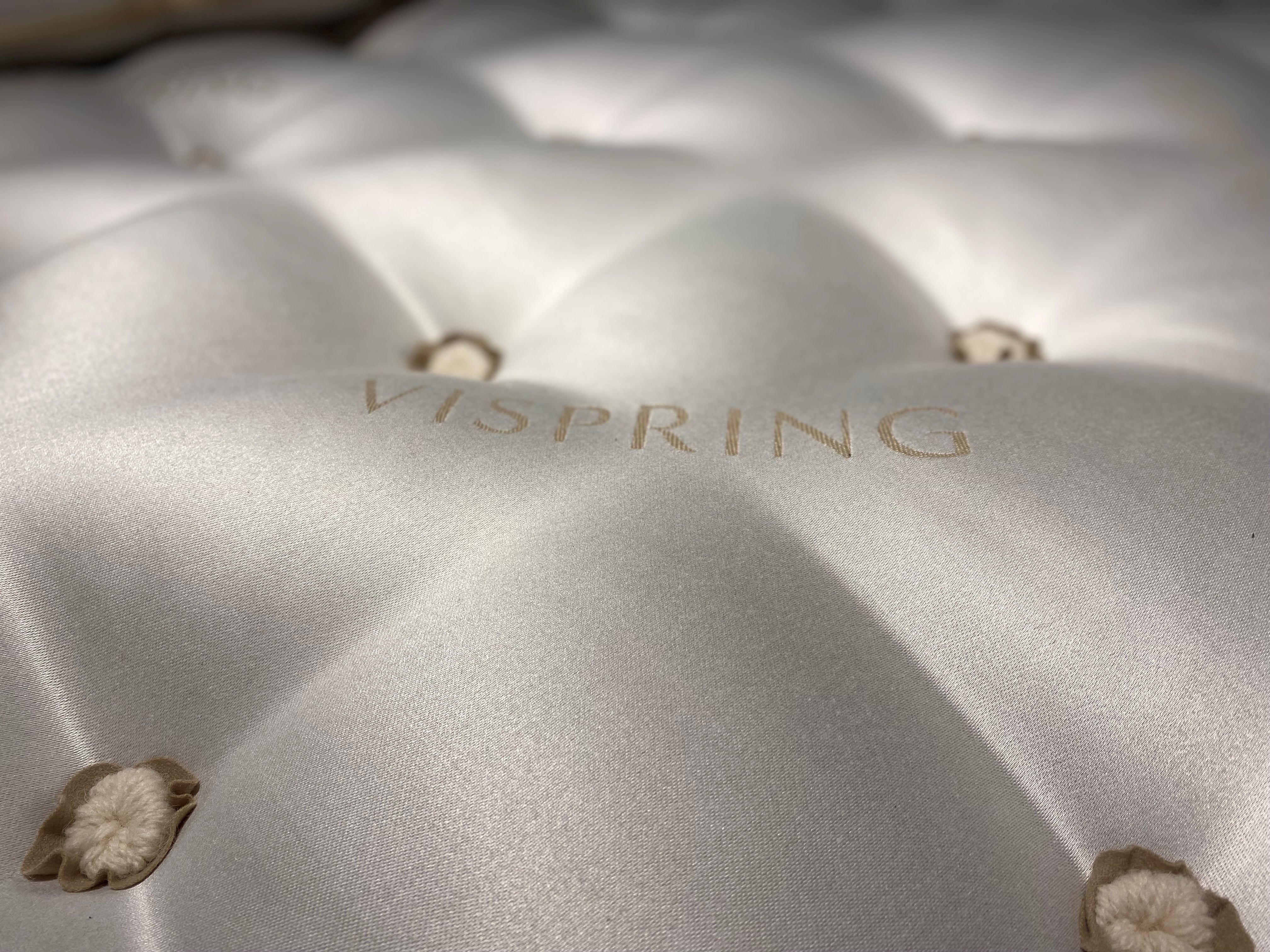 closeup of the top of a tufted luxury mattress with the word Vispring embroidered