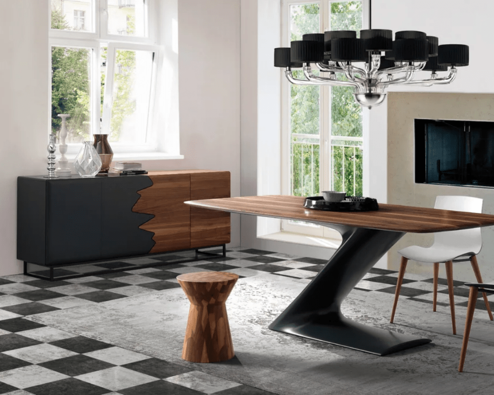 wooden dining table with accent sideboard under a modern chandelier by a fireplace
