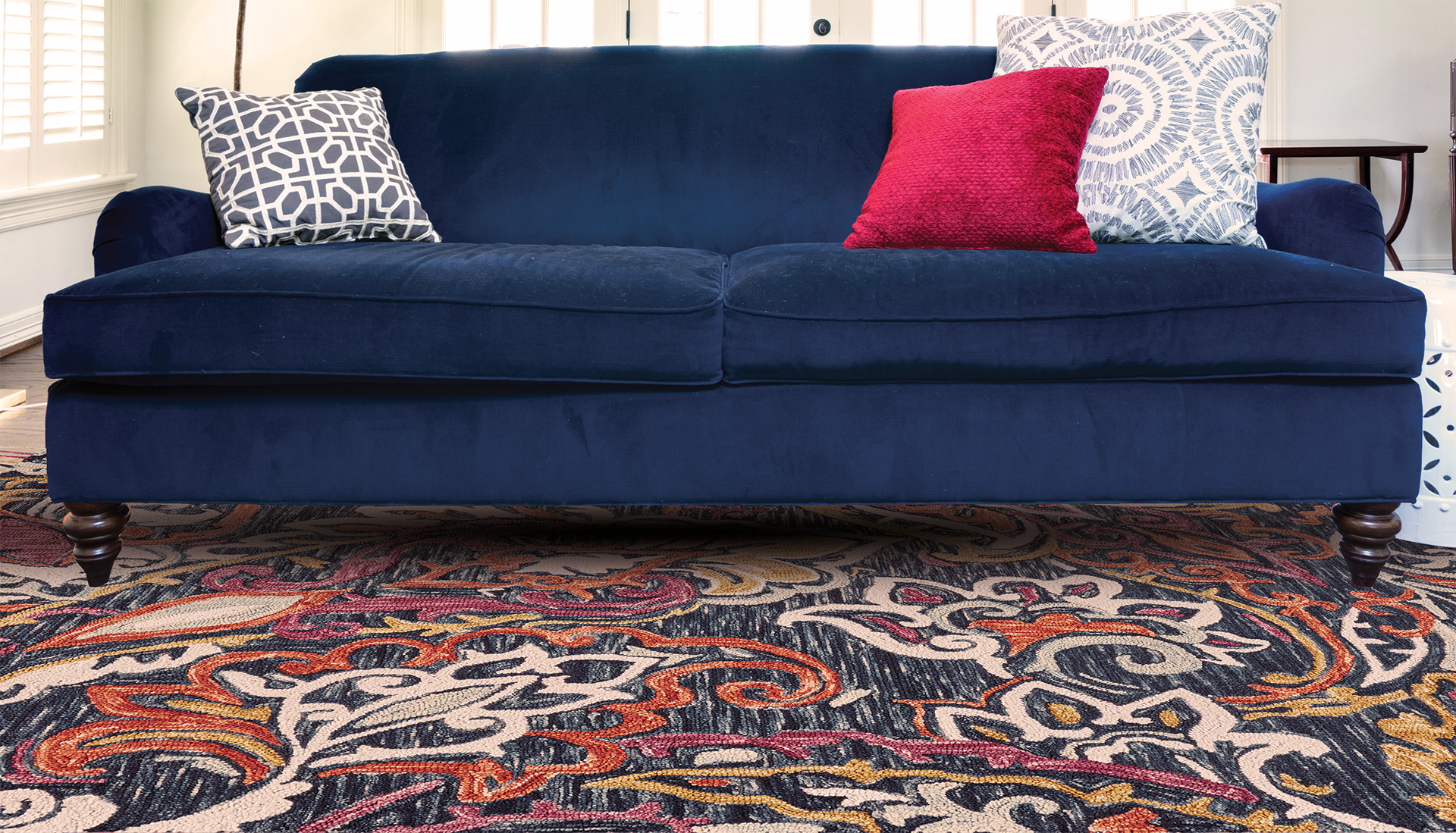 Feizy patterned area rug under two seater sofa with three throw pillows